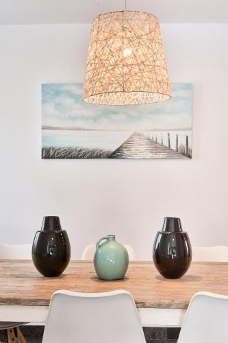 a dining room table with two vases and a painting at Casa Bianca in Cala Vadella
