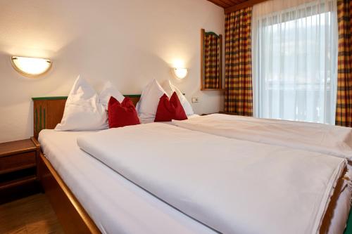a bedroom with a large white bed with red pillows at Bio-Pension Bliem in Altenmarkt im Pongau