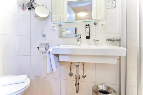 a white bathroom with a sink and a toilet at Bio-Pension Bliem in Altenmarkt im Pongau