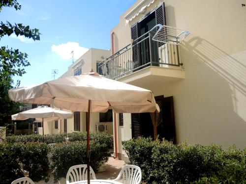 an umbrella and chairs in front of a building at Casa Vacanze Metrosideros in San Vito lo Capo