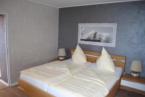 1 dormitorio con 1 cama con sábanas y almohadas blancas en Terrassenhaus Penthouse-Wohnung 93, en Cuxhaven