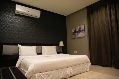 a bedroom with a large bed with white sheets at Triple Tree in Al Hofuf