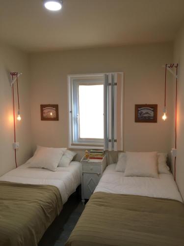 two beds in a room with a window at Casa do Gato que queria ser Pescador in Peniche