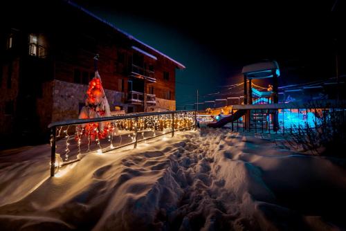 a fence with lights in the snow at night at Modern Apartment in Villa Monte in Bakuriani