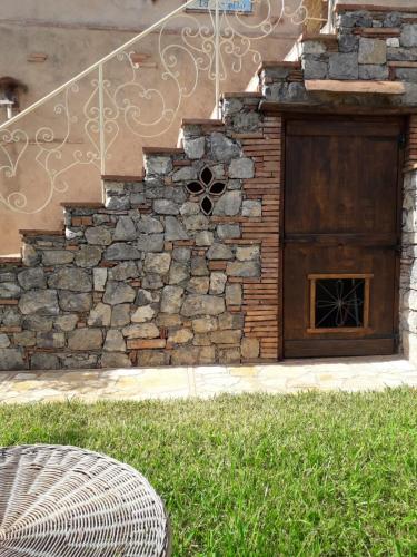 a building with a stone wall and a wooden door at B&B La Torretta in Maratea