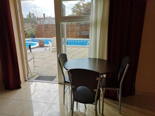 a table and chairs in a room with a sliding glass door at Borostyán Panzió Balatonfüred in Balatonfüred