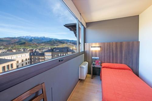 a bedroom with a red bed and a large window at Hotel Avenida in La Seu d'Urgell