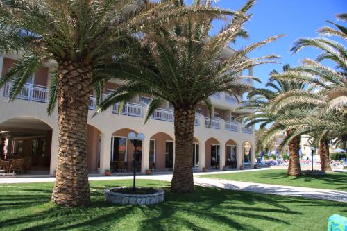 a group of palm trees in front of a building at Zakantha Beach in Argasi