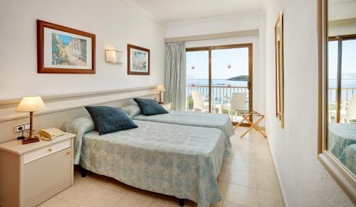a bedroom with a bed and a view of the ocean at Hotel Moré in Alcudia