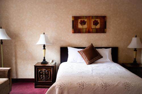 a bedroom with a bed with two lamps and a picture on the wall at Royal Inn and Suites at Guelph in Guelph