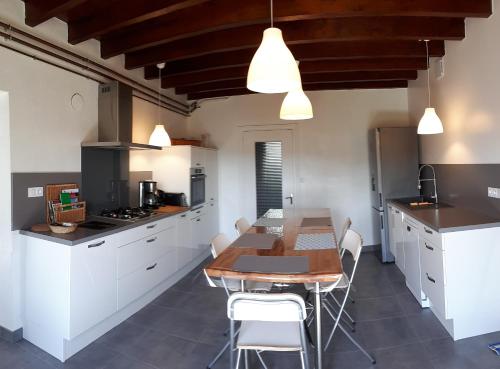 une cuisine avec une table en bois et des armoires blanches dans l'établissement Grand Gite Maison d Alice Auvergne - 15 personnes, à Saint-Bonnet-les-Quarts