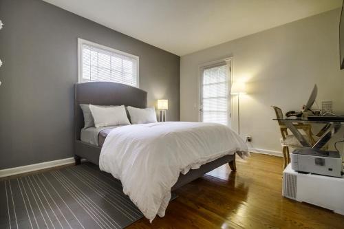 a bedroom with a bed with white sheets and a window at A Touch of Cape Cod in West Hollywood in Los Angeles