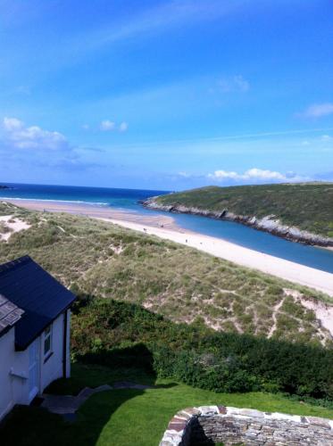 a view of a beach with a building and the ocean at Chy-an-Lowena in Crantock