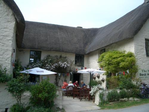 a group of people sitting under umbrellas outside of a building at Chy-an-Lowena in Crantock