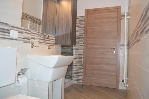 a bathroom with a white sink and a wooden door at Parravicini Red Flower apartment in Tirano