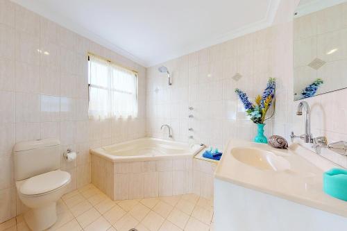 a bathroom with a toilet and a tub and a sink at Paradise Beach Apartments in Sanctuary Point