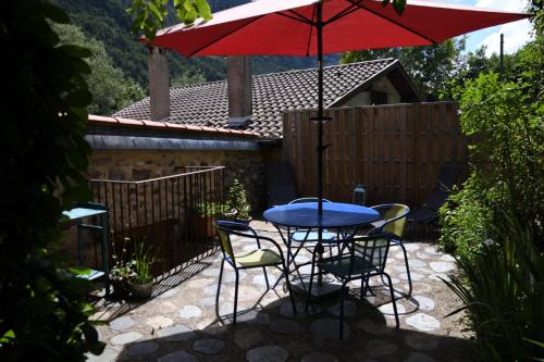- une table et des chaises avec un parasol rouge sur la terrasse dans l'établissement Arcogite, à Vicdessos