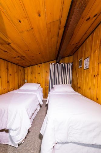 two beds in a room with wooden walls and ceilings at Siena Hotel in Campos do Jordão