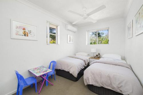 two beds in a room with a table and chairs at Seabreeze 4 on Lawson Street in Byron Bay