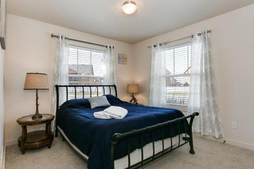 a bedroom with a bed with blue sheets and two windows at Gray Cloud Townhomes in Meridian