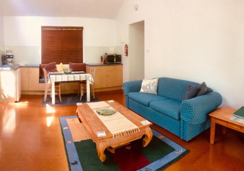 sala de estar con sofá azul y mesa en Byron Beach Cabin en Byron Bay