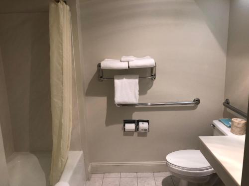 a bathroom with a toilet and a shower and towels at The Monarch Resort in Pacific Grove