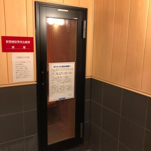 a door in a bathroom with a sign on it at Hotel Tsukuba Hills Gakuen-odori in Tsukuba