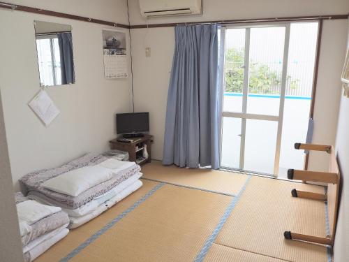 a room with two beds and a sliding glass door at Pension New Hamanoso in Ishigaki Island