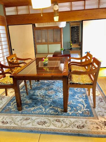 a dining room with a table and chairs on a rug at Tubakiann in Kikuchi