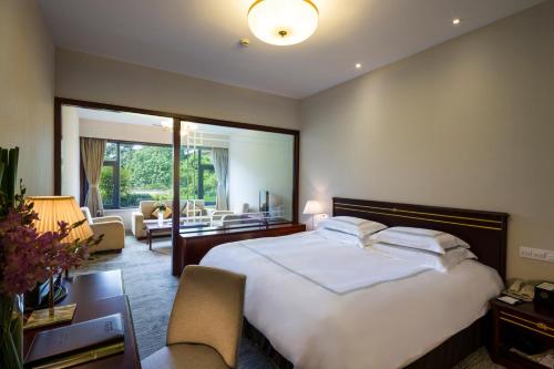a bedroom with a large bed and a living room at Zhejiang Xizi Hotel in Hangzhou