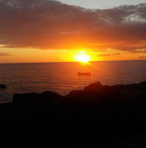 a sunset over the ocean with a boat in the water at Kanalu Studio in Bouillante