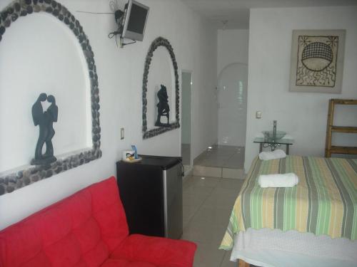 a bedroom with a bed and a red couch at Hotel Villas del Rey in Chachalacas