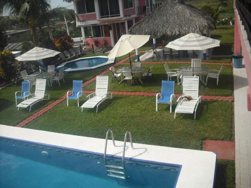 vistas a una piscina con sillas, mesas y sombrillas en Hotel Villas del Rey, en Chachalacas