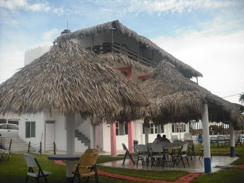 a building with chairs and a table and a straw hut at Hotel Villas del Rey in Chachalacas