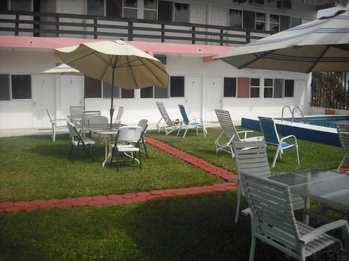 a patio with tables and chairs and an umbrella at Hotel Villas del Rey in Chachalacas