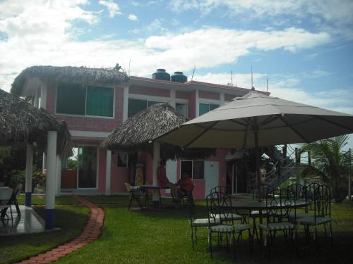 a pink house with tables and chairs and an umbrella at Hotel Villas del Rey in Chachalacas