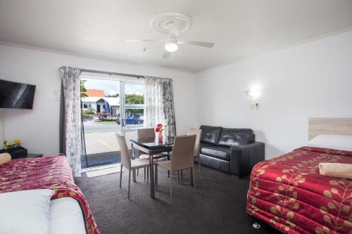 una habitación de hotel con una mesa y sillas y un dormitorio en Rose Court Motel, en Rotorua