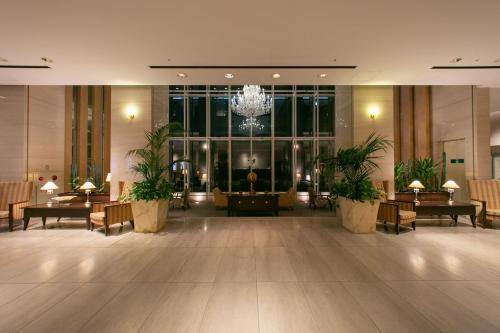 a lobby with tables and chairs and a chandelier at KKR Hotel Kanazawa in Kanazawa