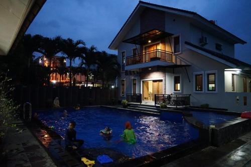 due bambini che giocano in una piscina di fronte a una casa di Pesona Air - Villa and Private Pool a Depok