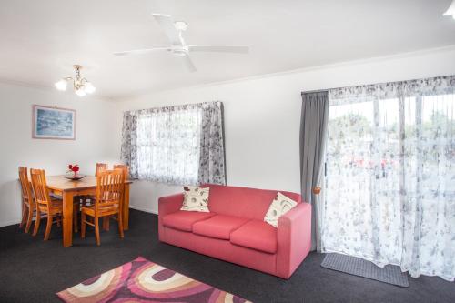 a living room with a red couch and a table at Rose Court Motel in Rotorua