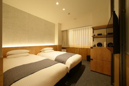 a hotel room with two beds and a television at Hotel Oriental Express Tokyo Kamata in Tokyo
