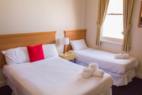 Habitación de hotel con 2 camas y toallas. en Gardners Inn Hotel, en Blackheath