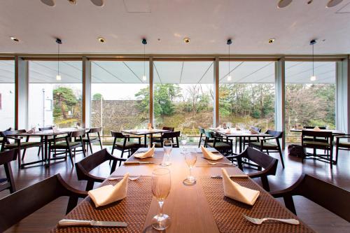 a restaurant with tables and chairs and large windows at KKR Hotel Kanazawa in Kanazawa