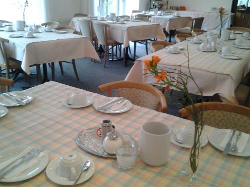 uma sala de jantar com mesas e cadeiras com toalha de mesa branca em Hotel Zimmermann em Filderstadt