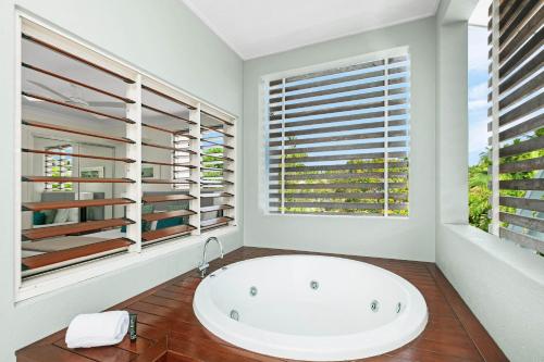 a bathroom with a large white tub and windows at Mantra Aqueous on Port in Port Douglas
