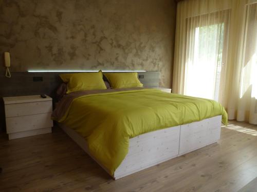 a bedroom with a large bed with a yellow blanket at Hotel al Sole in Auronzo di Cadore