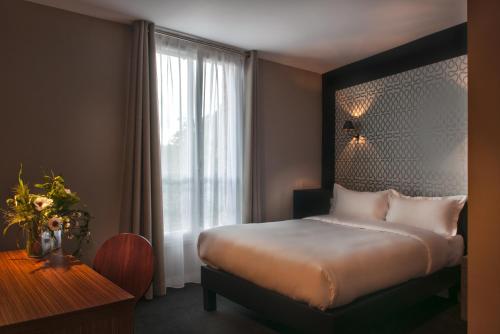 een slaapkamer met een bed, een raam en een tafel bij Hotel Les Terres Blanches in Chatou