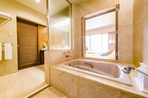Yaese的住宿－南方林克斯度假飯店，一间带浴缸和大镜子的浴室