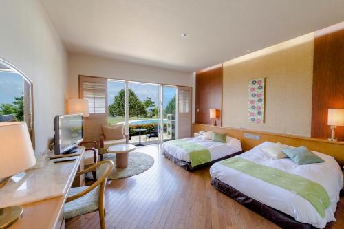 Habitación de hotel con 2 camas, escritorio y TV. en The Southern Links Resort Hotel en Yaese