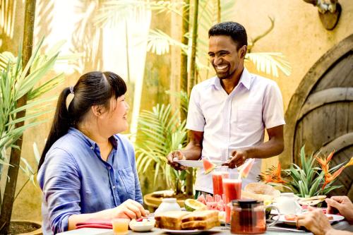 a man serving a woman a plate of food at a table at Small House Boutique Guest House in Galle